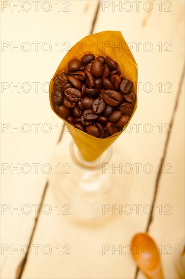 Espresso coffee beans on a paper cone cornucopia over white background