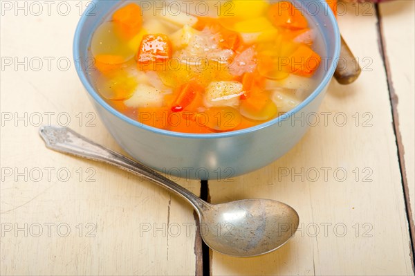 Traditional Italian minestrone soup on a rustic table with ingredients