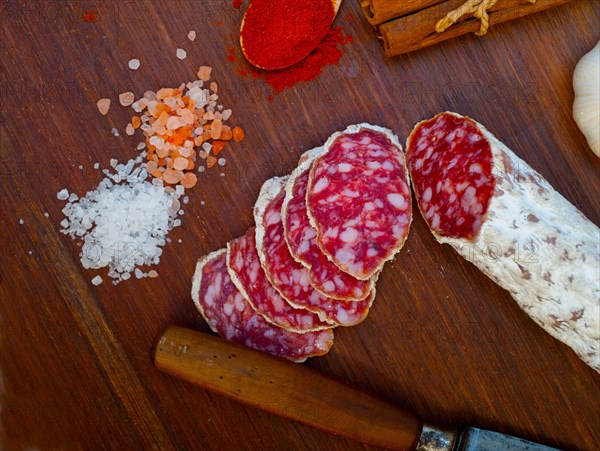 Traditional Italian salame cured sausage sliced on a wood board