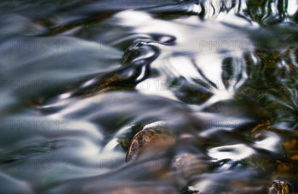 flowing water flows over stones with light reflections