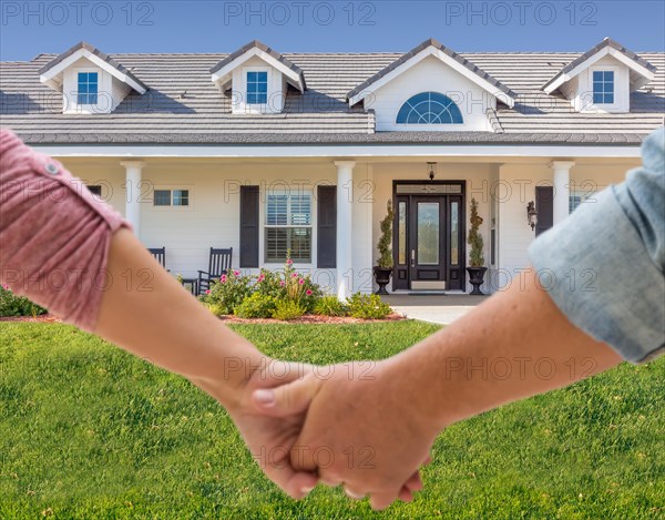 A couple hold his hands approaching the front door of a new house