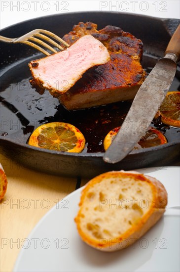 Pork chop seared on iron skillet with lemon and spices seasoning
