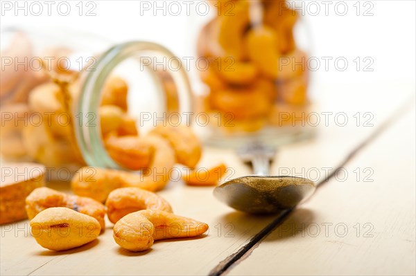 Cashew nuts on a glass jar over white rustic wood table