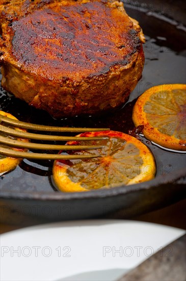 Pork chop seared on iron skillet with lemon and spices seasoning