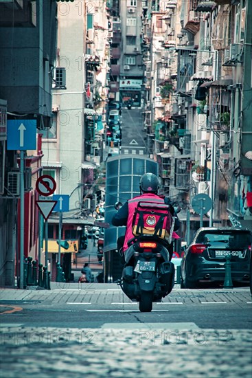 Adeliveryman on motorcycle on the street in Macau