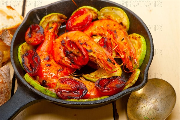 Roasted shrimps on cast iron skillet with zucchini and tomatoes