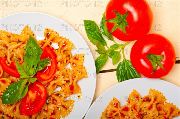 Italian pasta farfalle butterfly bow-tie with tomato basil sauce over white rustic wood table