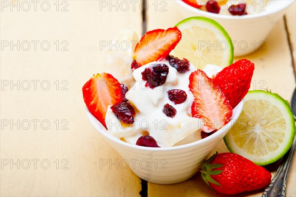 Fruit and yogurt salad healthy breakfast over white wood table