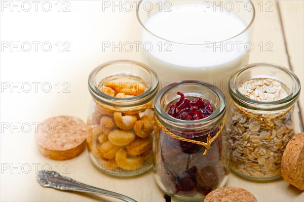 Healthy breakfast ingredients milk oat cashew nuts dried cramberry craisinns