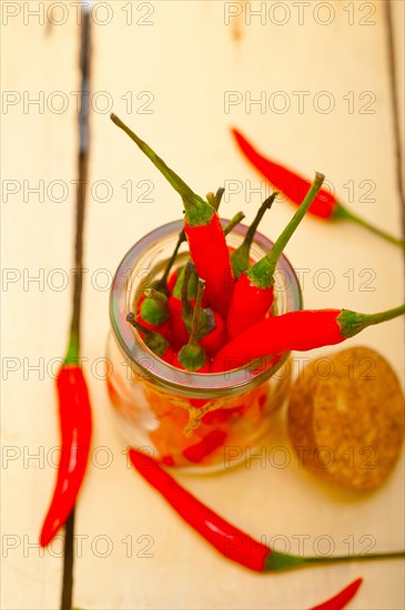 Red chili peppers on a glass jar over white wood rustic table