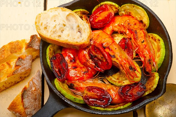 Roasted shrimps on cast iron skillet with zucchini and tomatoes