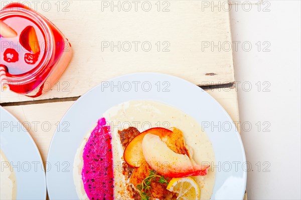 Sea bream orata fillet butter pan fried with fresh peach prune and dragonfruit slices thyme on top