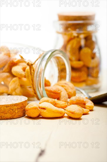 Cashew nuts on a glass jar over white rustic wood table