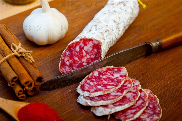 Traditional Italian salame cured sausage sliced on a wood board