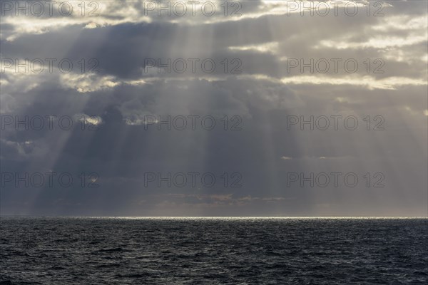 Sun breaks through the clouds with sunrays over sea