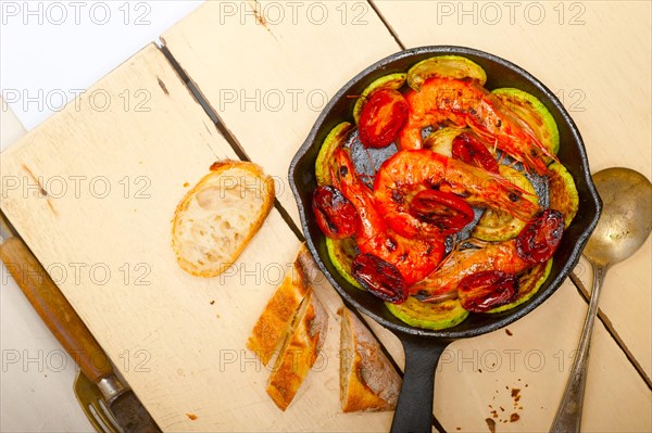 Roasted shrimps on cast iron skillet with zucchini and tomatoes