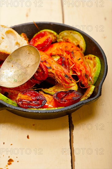 Roasted shrimps on cast iron skillet with zucchini and tomatoes