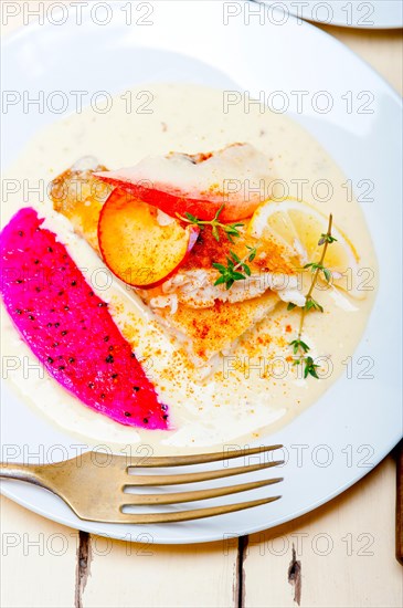 Sea bream orata fillet butter pan fried with fresh peach prune and dragonfruit slices thyme on top