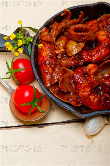 Fresh seafood stew prepared on an iron skillet ove white rustic wood table