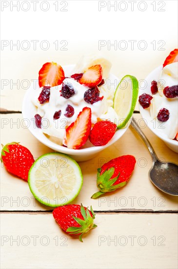 Fruit and yogurt salad healthy breakfast over white wood table