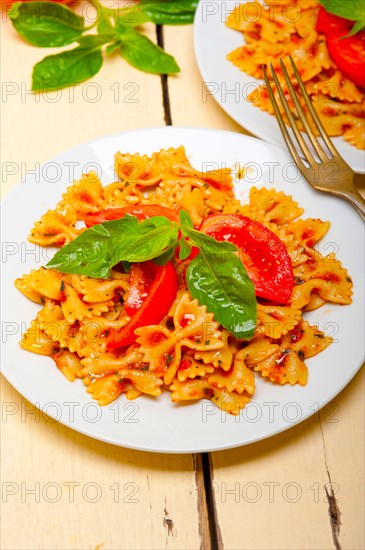 Italian pasta farfalle butterfly bow-tie with tomato basil sauce over white rustic wood table