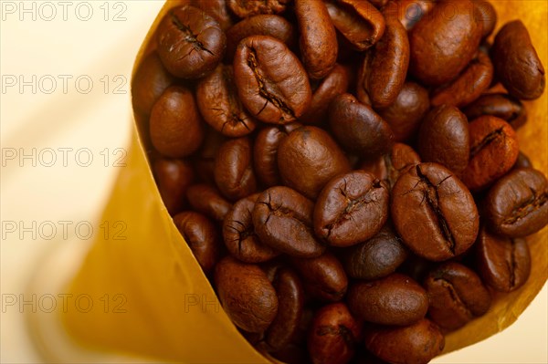 Espresso coffee beans on a paper cone cornucopia over white background