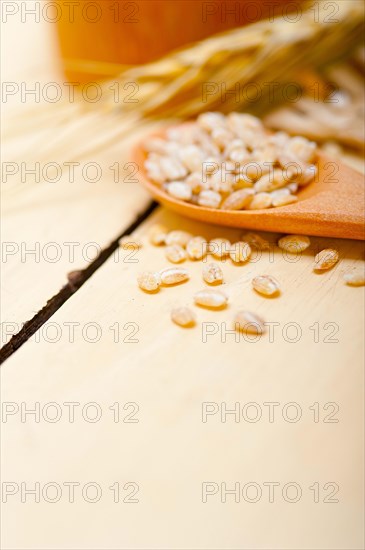 Organic wheat grains over rustic wood table macro closeup