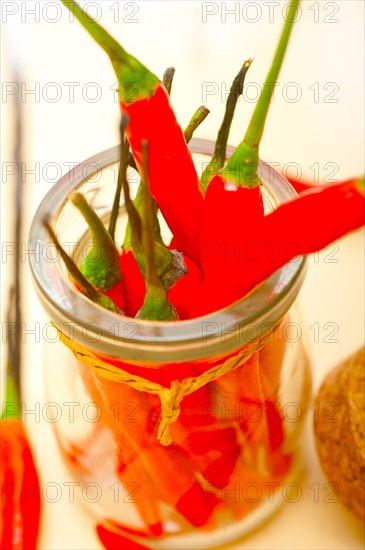 Red chili peppers on a glass jar over white wood rustic table