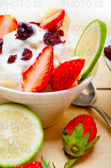 Fruit and yogurt salad healthy breakfast over white wood table