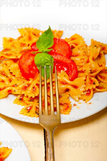 Italian pasta farfalle butterfly bow-tie with tomato basil sauce over white rustic wood table