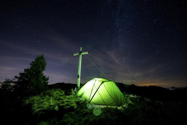 Green tent with summit cross under a starry sky on Portlakopf