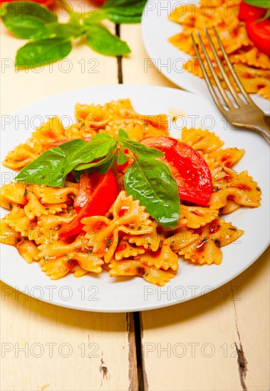 Italian pasta farfalle butterfly bow-tie with tomato basil sauce over white rustic wood table