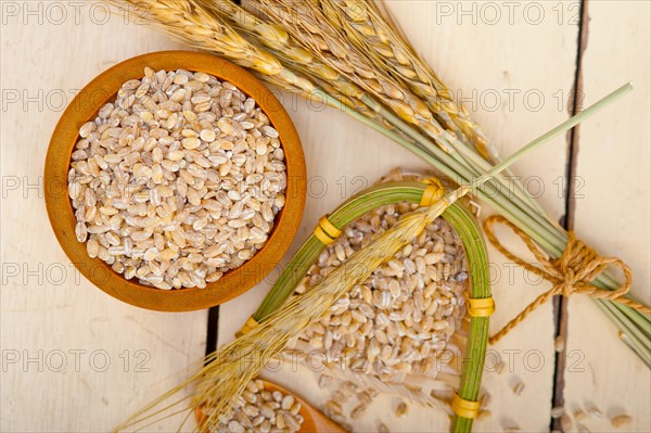 Organic wheat grains over rustic wood table macro closeup