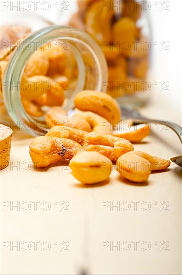 Cashew nuts on a glass jar over white rustic wood table