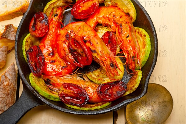 Roasted shrimps on cast iron skillet with zucchini and tomatoes