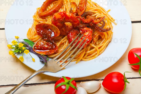 Italian seafood spaghetti pasta on red tomato sauce over white rustic wood table