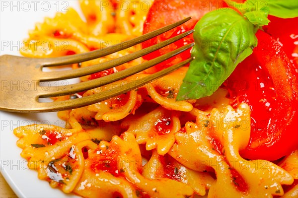 Italian pasta farfalle butterfly bow-tie with tomato basil sauce over white rustic wood table