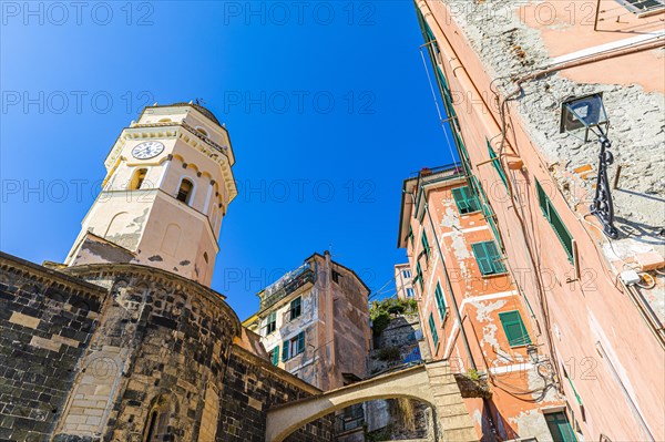The steeple of the church of Santa Margherita di Antiochia and nested houses built into the hillside with pastel-coloured facades