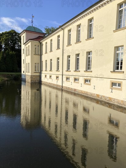View of classicist castle Westerholt with reflection of building in historical moat