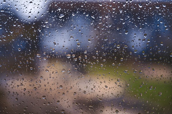 Raindrops on a window pane of an apartment building during a heavy thunderstorm