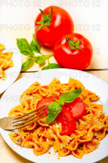 Italian pasta farfalle butterfly bow-tie with tomato basil sauce over white rustic wood table