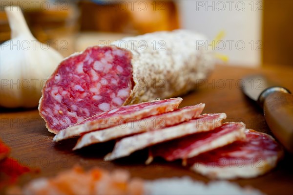 Traditional Italian salame cured sausage sliced on a wood board