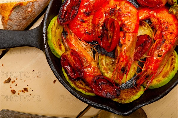 Roasted shrimps on cast iron skillet with zucchini and tomatoes