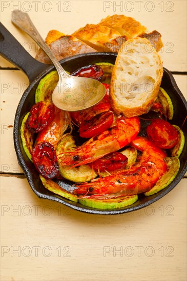 Roasted shrimps on cast iron skillet with zucchini and tomatoes