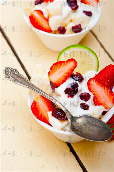 Fruit and yogurt salad healthy breakfast over white wood table