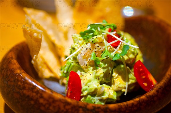 Fresh avocado and shrimps salad with nachos on side