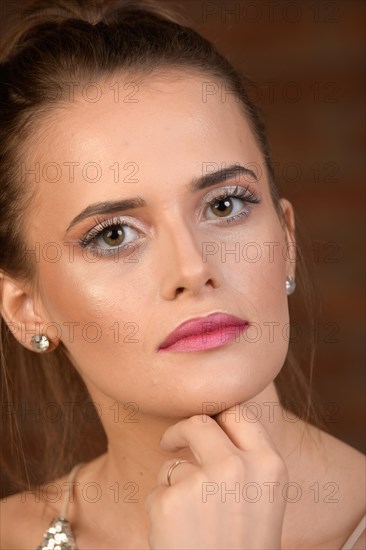 Pretty young woman with long hair and discreet make-up against a brown background