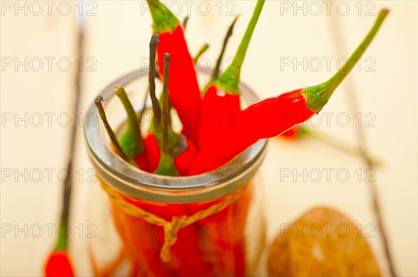 Red chili peppers on a glass jar over white wood rustic table