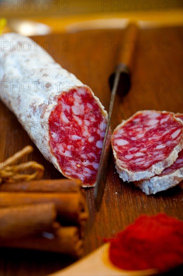 Traditional Italian salame cured sausage sliced on a wood board