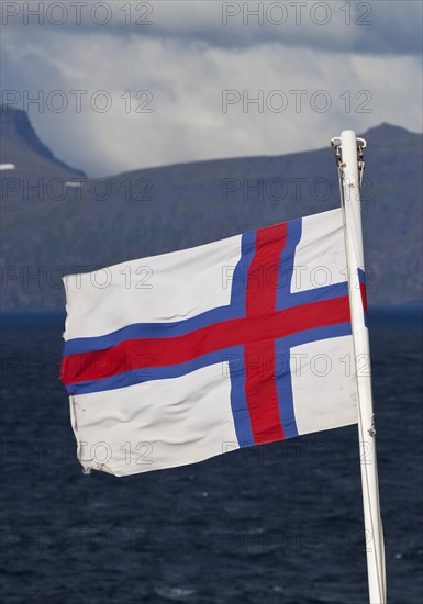 Flag of the Faroe Islands in front of the North Atlantic Ocean